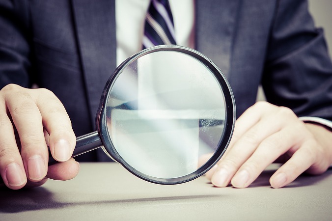 虫眼鏡を持つスーツの人